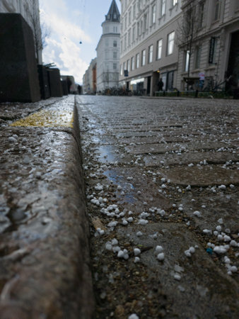 Braving the elements, this cobblestone street takken at a low angle wears a wintry coat of small white hailstones.の写真素材