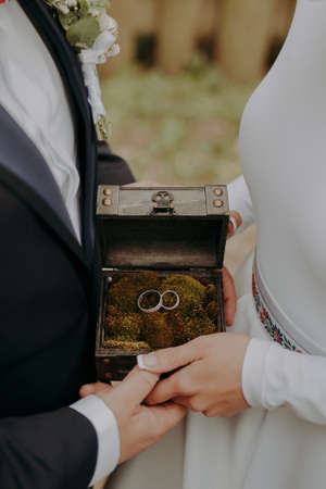 gold wedding rings in box with moss in hands