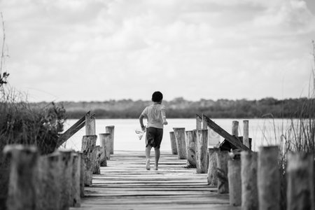 Boy running on the wooden bridge over the lake, black and whiteの写真素材