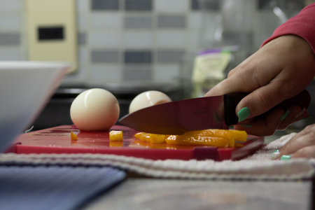Caucasian woman with manicured nails cutting bell peppers on board with knifeの写真素材