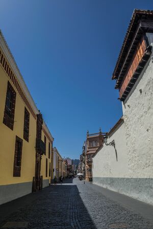 La Laguna, Tenerife, Spain; August 22 2018: La Laguna, Bishop Rey Redondo street, historical street view, half in shadow the other with sun, and with blue sky, and some people walkingのeditorial素材