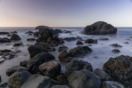 Volcanic rocks in Atlantic ocean, long exposure photography, horizon with sunset light, San Juan de...