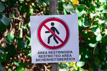 Restricted area sign, written in three languages, with vegetation backgroundの写真素材
