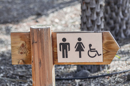 wooden bathroom direction sign, in a sunny park