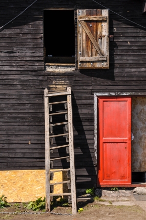 Wooden ladder on a cottage wall with red doorの写真素材
