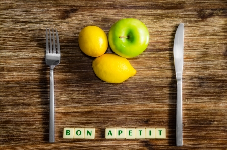 Lemons and apple on wooden vintage table with silverware and Bon apetit signの写真素材