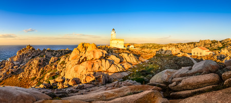Rocky ocean coastline panorama with lighthouse at sunset, Sardinia, Italyの写真素材