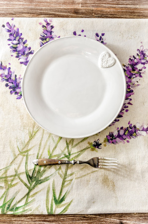 Plate and fork on vintage wooden dining table with colorful tableclothの写真素材