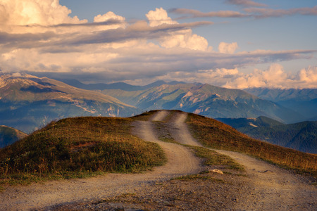 Mountain landscape view with curvy road and colorful sunset clouds, Svaneti, Country of Georgiaの写真素材