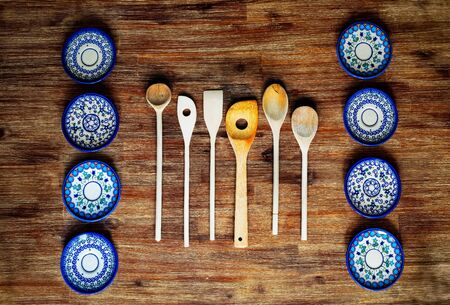 Detail of wooden cooking spoons and painted ornate plates on textured wooden table in vintage styleの写真素材