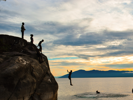 Cliff diving against a golden sunset, Kande Beach, Nkhata Bay, Lake Malawi