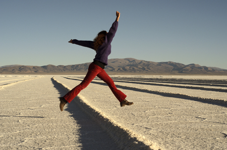Girl with colorful clothes jumping with joy on the saltの写真素材