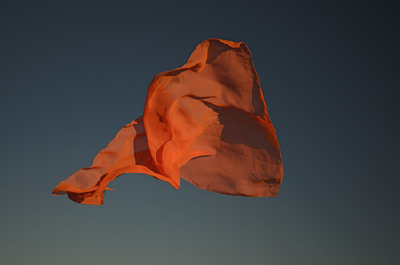 Orange scarf flying in the sun with sky backgroundの写真素材