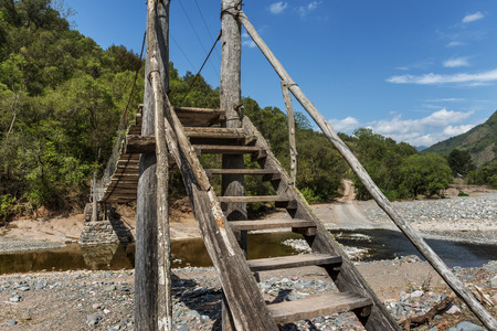 Hanging wooden bridge over river in the Latin American jungleの写真素材