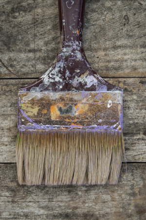 used brush with bits of dried paint on wood backgroundの写真素材