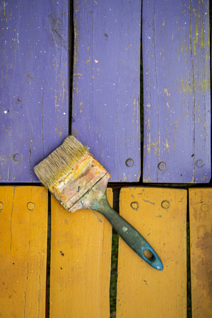 used brush with bits of dried paint on colored wood backgroundの写真素材