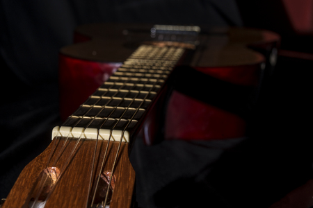 approach to a detali of Spanish guitar on black background