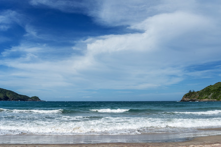 image of a bay with beach and waves and green hillsの写真素材
