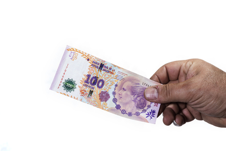 Hand of man holding a hundred Argentinean peso bill in which the face of Eva Peron appears. All isolated on white backgroundの写真素材