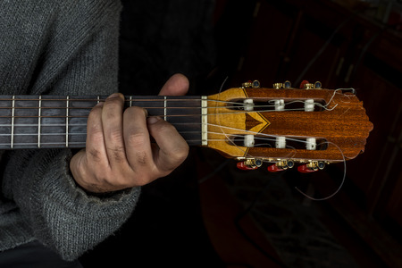 Left hand of man who is playing the guitar