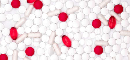 Pharmaceutical industry, healthcare and pharmacy top view on red and white vitamins, pills and capsules medicines scattered on white background, flat layの写真素材