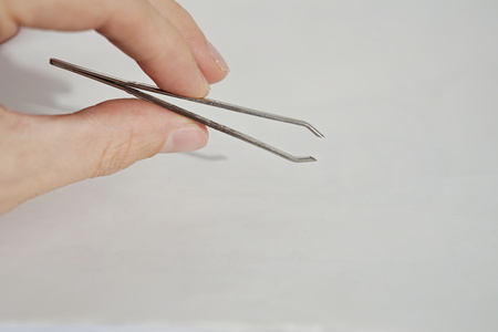Isolated male hand holding silver tweezers (cosmetic pincer used for face cultivation)の写真素材