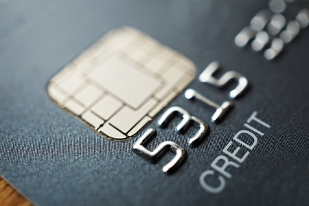 Macro detail of a brand new black and gray luxurious credit card with focus on the caption Credit, metal electronic chip and embossed numbers and lettersの写真素材