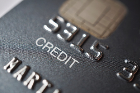 Macro detail of a brand new black and gray luxurious credit card with focus on the caption Credit, metal electronic chip and embossed numbers and lettersの写真素材