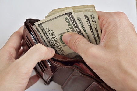 Male hand withdrawing American currency (US Dollars) from walletの写真素材