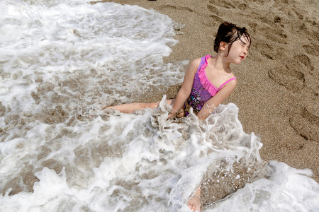 children playing in the water with the waves at the beachの写真素材