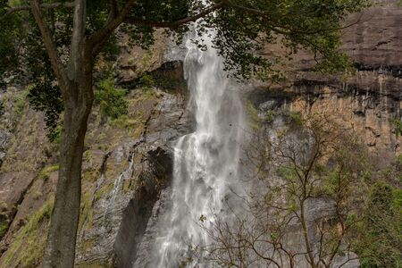 Sunny day in the Tropical waterfall falls from the mountain cliff to the jungle, serene landscape of...