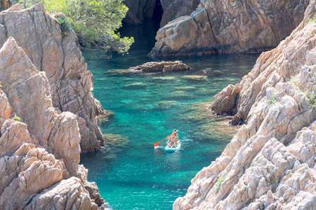 Sant Feliu de Guixols, Spain: 02 Sept 2020: Three young girls go paddle surfing in the Village of Sant Feliu de Guixols at Costa Brava in Catalonia, Mediterranean Sea, Spain in summer 2020のeditorial素材