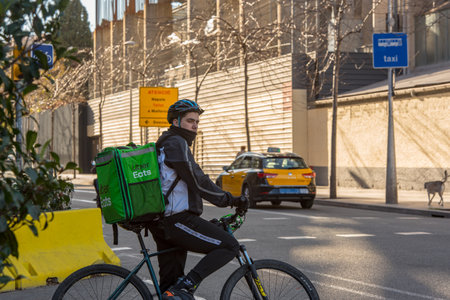 Barcelona, Spain: December 30 2020: Uber eats behind Basicila and Expiatory Church of the Holy Family, known as Sagrada Familia at sunset in COVID Time.のeditorial素材