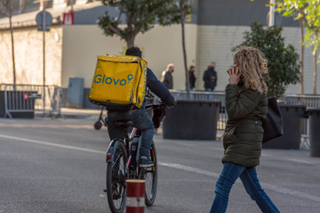 Barcelona, Spain: December 30 2020: Glovo behind Basicila and Expiatory Church of the Holy Family, known as Sagrada Familia at sunset in COVID Time.のeditorial素材
