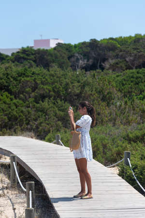 Formentera, Spain: July 11, 2021: Woman take a picture on the beach at Es Pujols beach in Formentera in summer 2021のeditorial素材