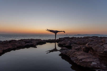Young man practicing yoga at Sunset in Can Marroig in Formentera, Spainの写真素材