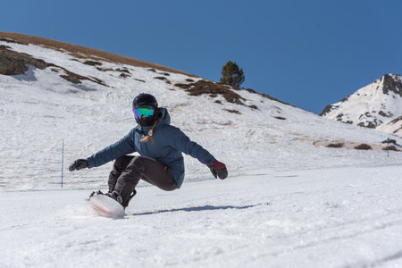 Young woman snowboarder in motion on snowboard in mountains.の写真素材