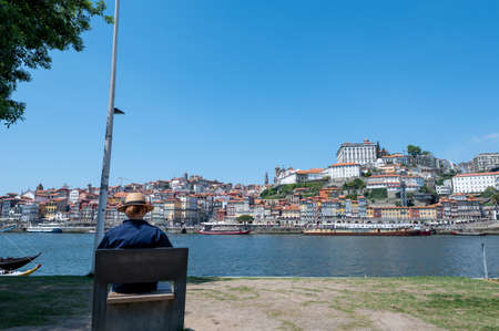 Woman with hat sitting on the shore of the Rio Douro in Porto, Portugal.のeditorial素材