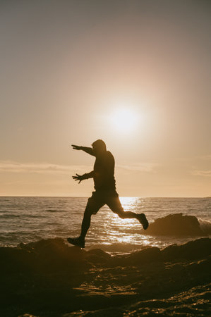 Silhouette of Man on the rocks watching the sunset.の写真素材