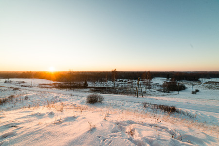 cold morning in the field in winter at countryside with snow and blue skiesの写真素材