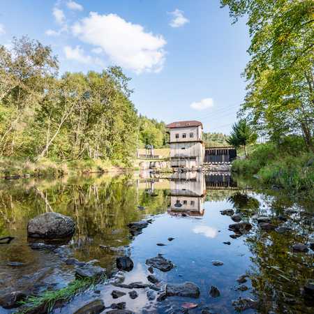 electric mill on a river in summer with stream and high water in forestの写真素材