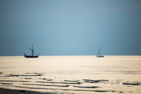 sea with waves and boats before sunset