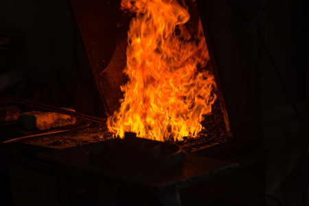 The blacksmith making flames in smithy with spark fireworks