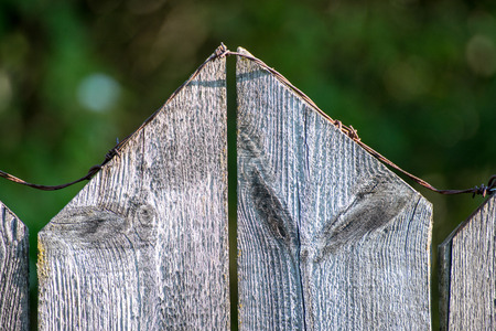 old wooden fence with barbed wire on topの写真素材