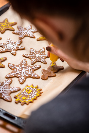 Womans hand decorating cookies with sugar. Making Gingerbread Cookies Series.の写真素材