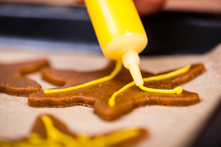 Womans hand decorating cookies with sugar. Making Gingerbread Cookies Series.の写真素材