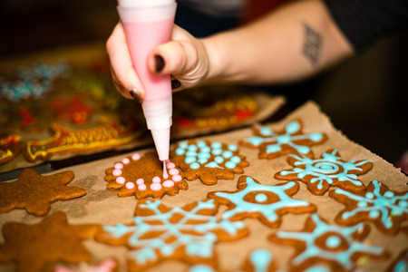 Womans hand decorating cookies with sugar. Making Gingerbread Cookies Series.の写真素材