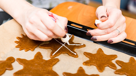 Womans hand decorating cookies with sugar. Making Gingerbread Cookies Series.