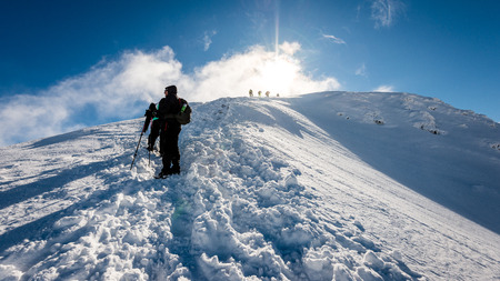 tourists enjoying high mountains in snow on a sunny day. sun and blue sky in slovakiaの写真素材