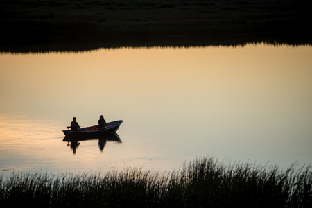 colorful orange sunrise over the lake in summer with small boatの写真素材